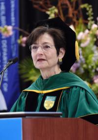 A women in academic robes speaks at a podium
